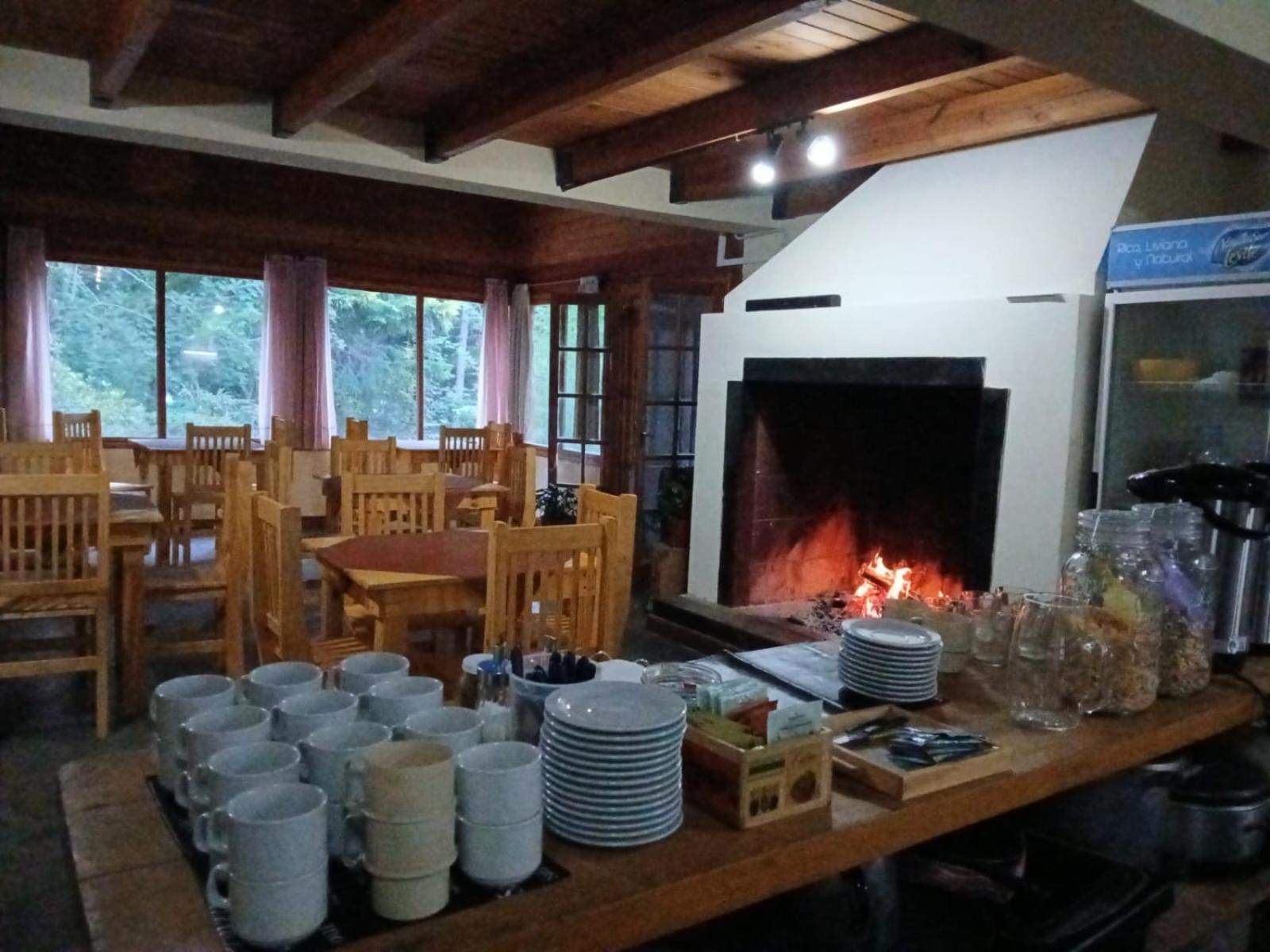 Comedor con hogar a leña encendido y mesas de madera