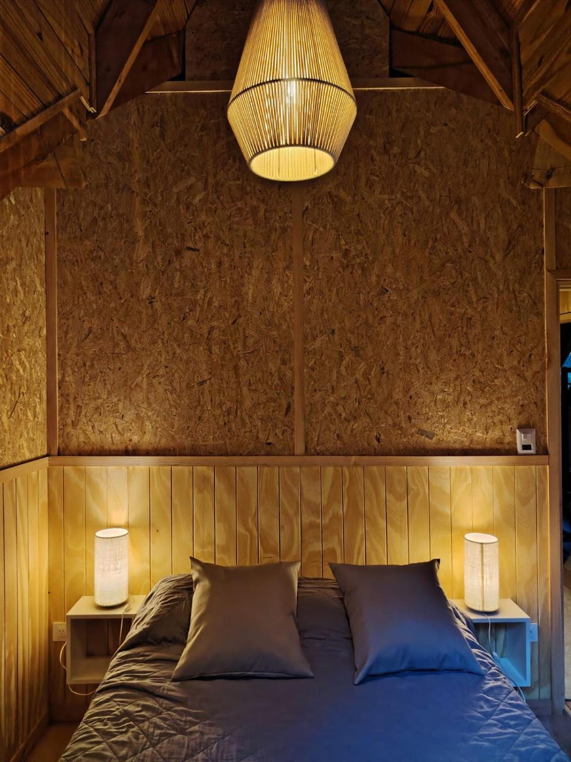 Cama doble con lámpara de mimbre y veladores