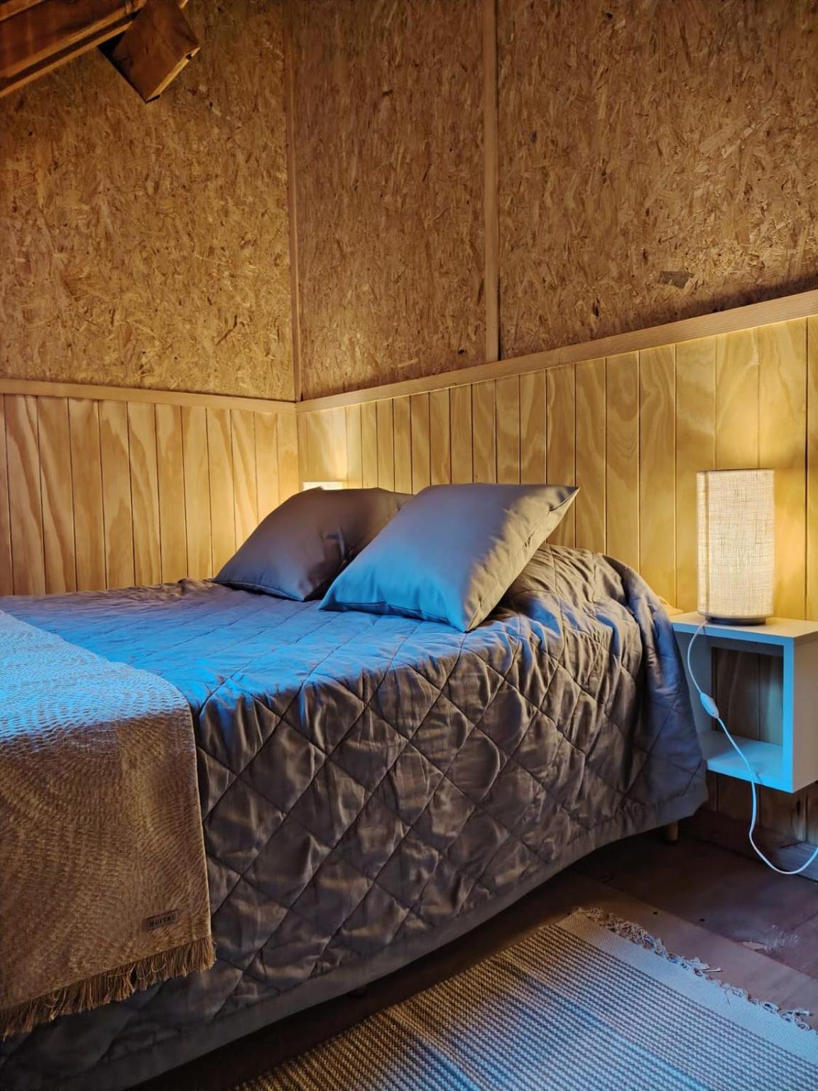 Cama doble con almohadones y velador