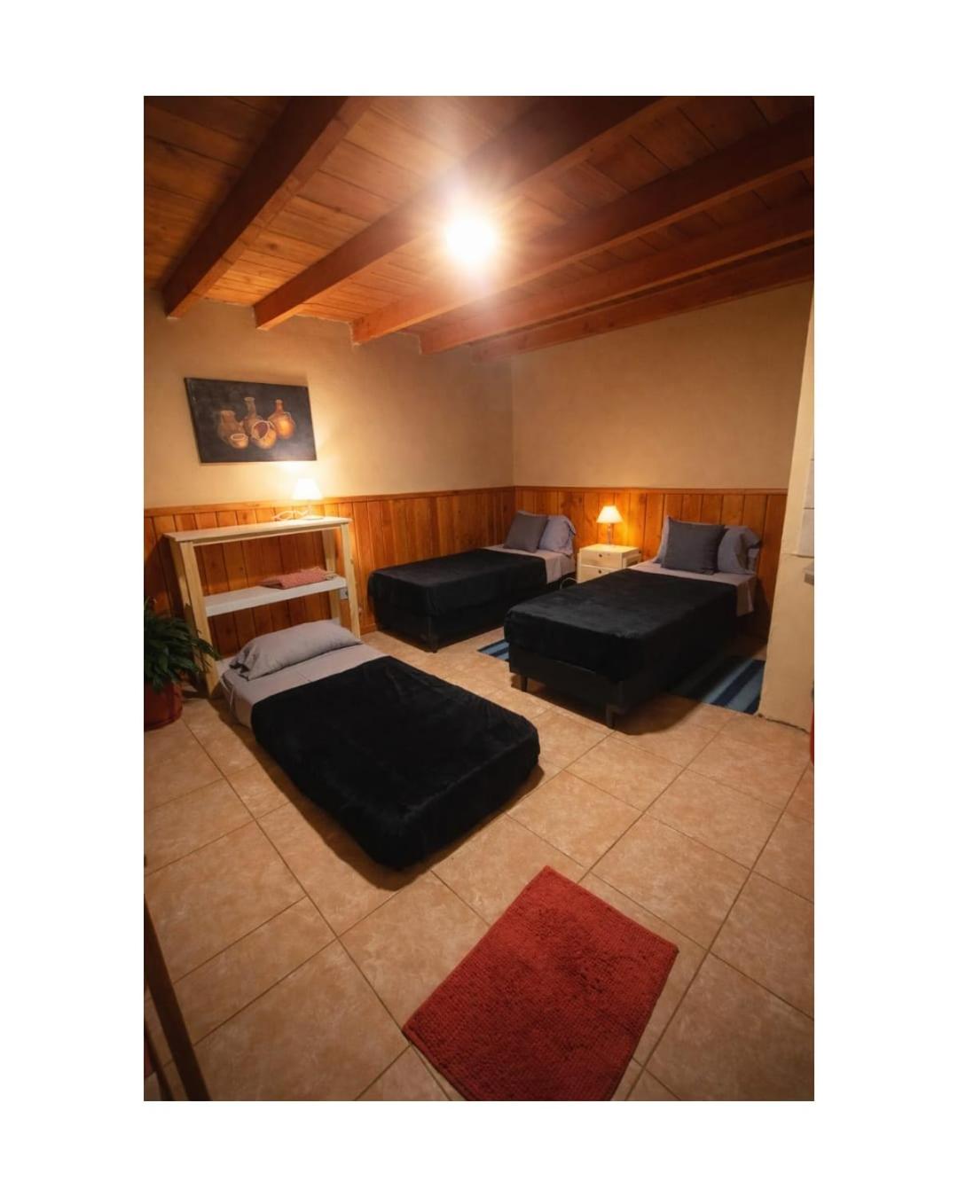 Habitación con tres camas bajas y techo de madera